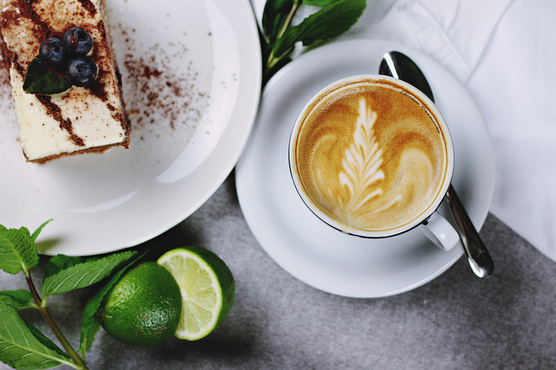 ภาพถ่ายเซ็ตกาแฟลาเต้อาร์ตและเค้กทีรามิสุบลูเบอร์รีที่น่าอร่อย เมนูแนะนำสำหรับรีวิวตามรอยตะวัน ค้นหาสถานที่กินที่เที่ยวพร้อมของหวานที่ดีที่สุด